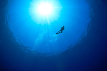 Silhouette of a snorkeller with sunbeams behind
